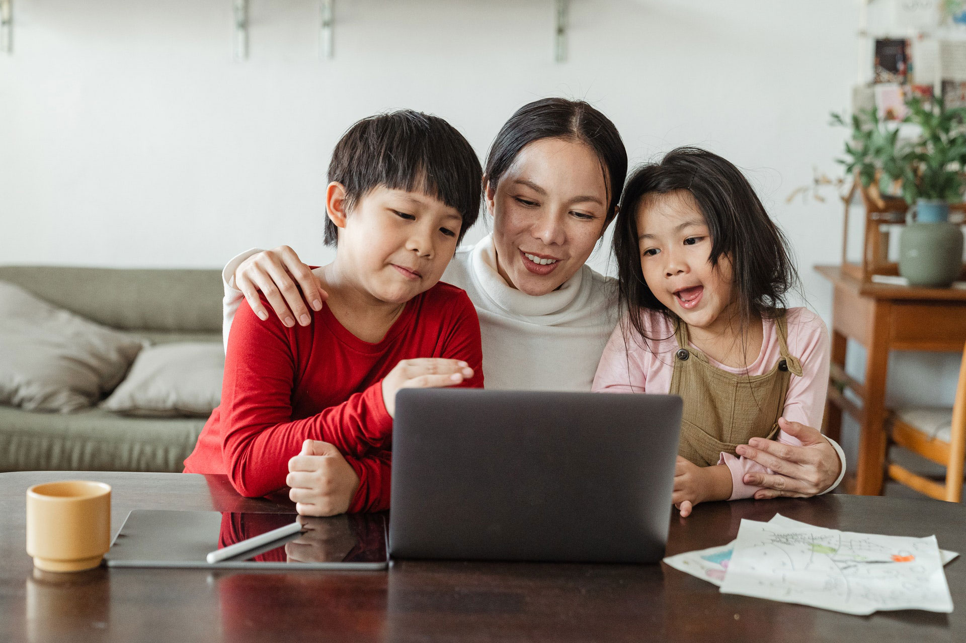 Mother with her son and daughter happily on computer at home