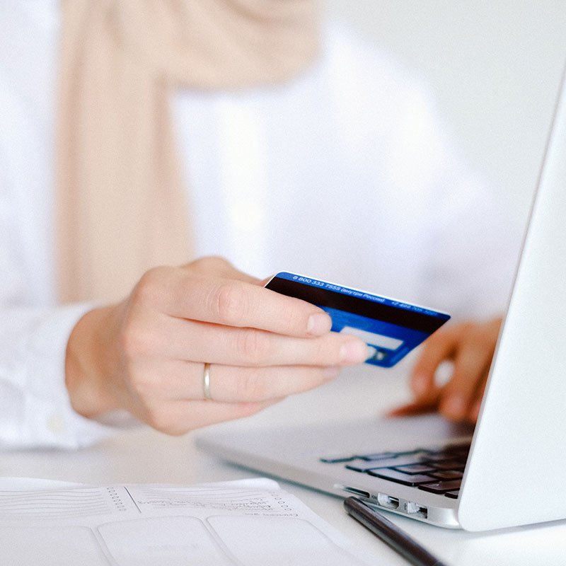 Person in White Long Sleeve Shirt Holding Credit Card on computer