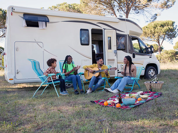 Family sitting outside RV having a picnic