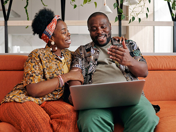 Happy couple on couch working on computer