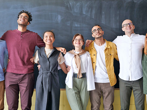 Work team members standing arm in arm smiling Work team members standing arm in arm smiling