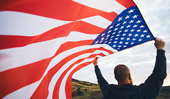 Man standing in a valley waving an American Flag