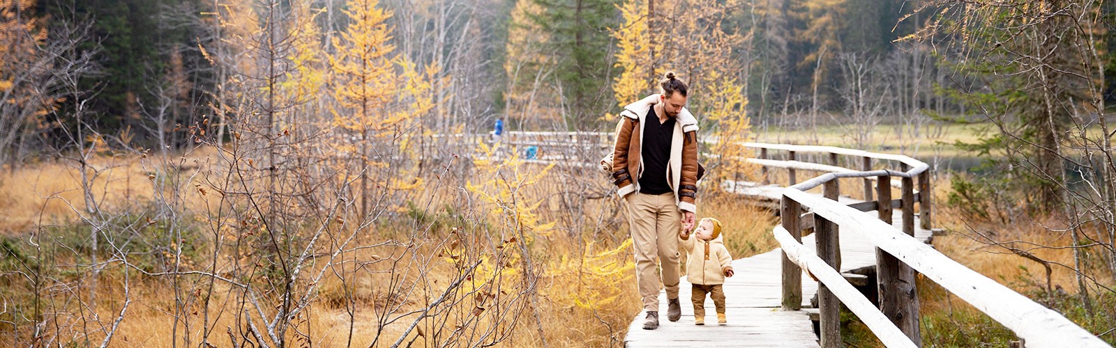 Man Walking On Wooden Bridge with child in Fall