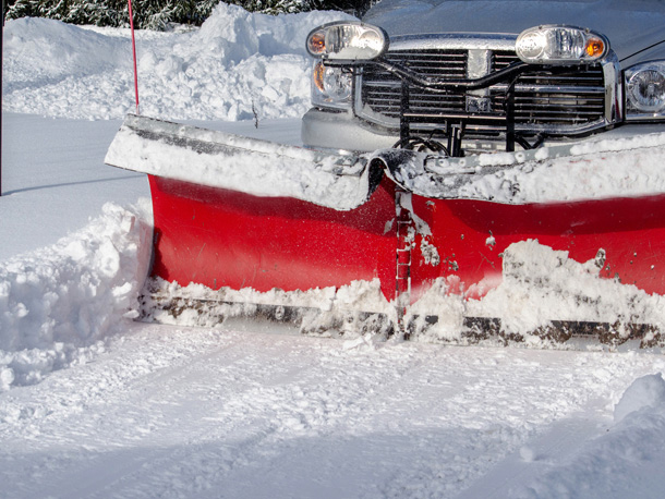 Pickup truck plowing snow with red snow plow shovel on