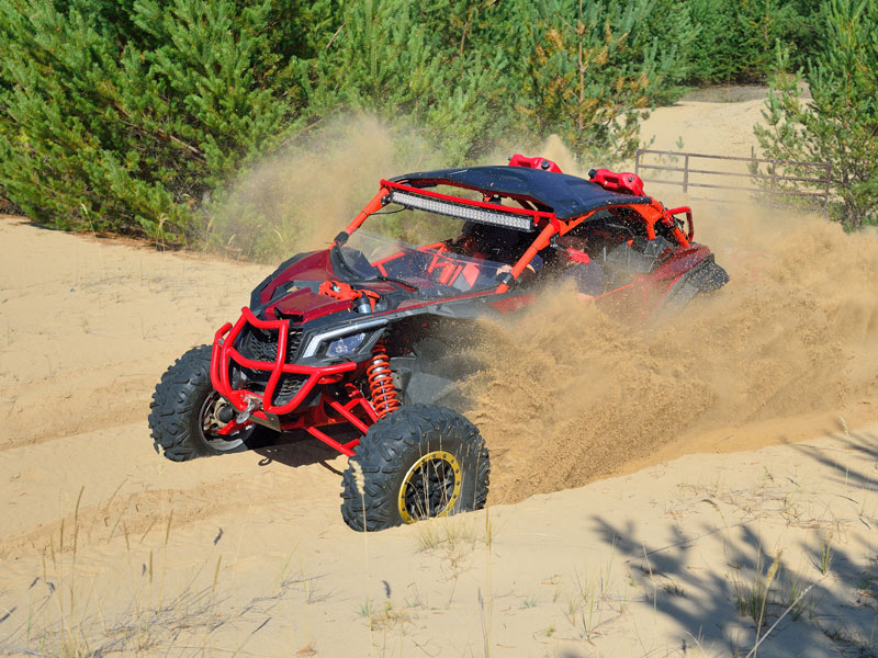 Off road vehicle driving through sand dunes by a forest Off road vehicle driving through sand dunes by a forest