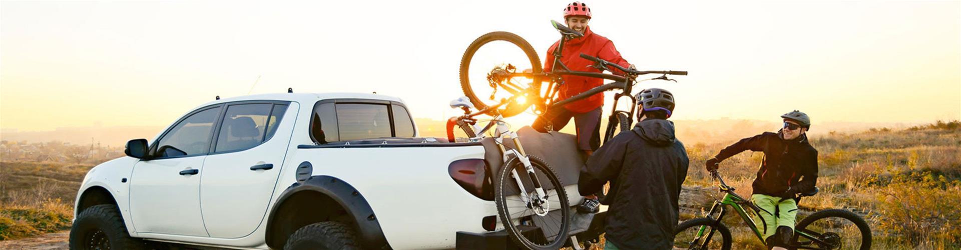 Group of friends unloading mountain bikes Guy standing in back of white truck unloading mountain bikes