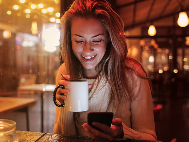 Woman in sweater Holding Mug happily Looking at Her Cellphone Woman in sweater Holding Mug happily Looking at Her Cellphone