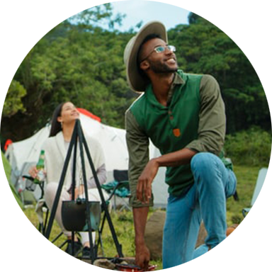 Black male camping, kneeling on the ground and looking to the sky optimistically