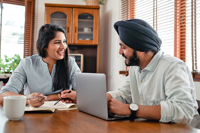 Happy couple sitting at a table with a laptop and documents Happy couple sitting at a table with a laptop and documents