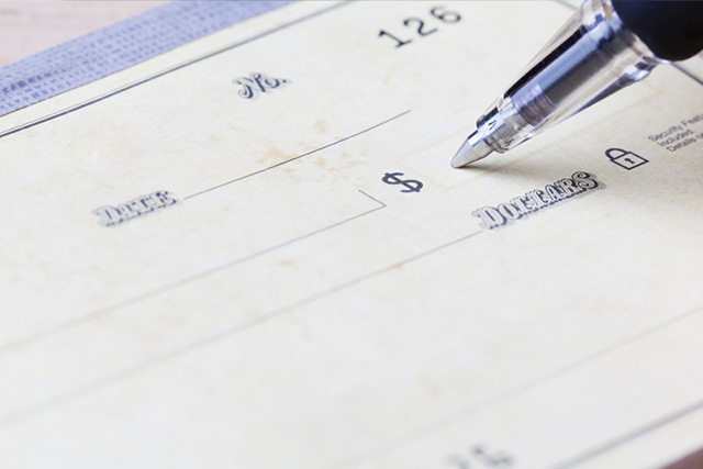Pen filling out a financial check Pen filling out a financial check
