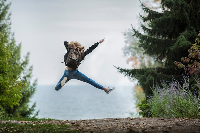Female on a hiking trail in a forest jumping in the air Female on a hiking trail in a forest jumping in the air